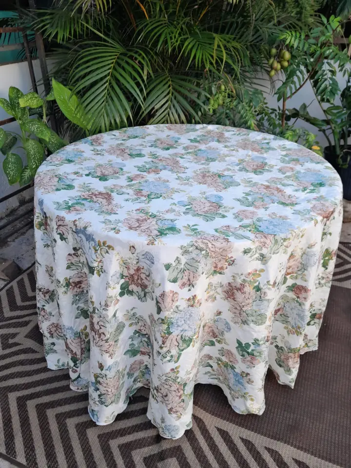 Mesa redonda em um jardim, com toalha floral em tons claros