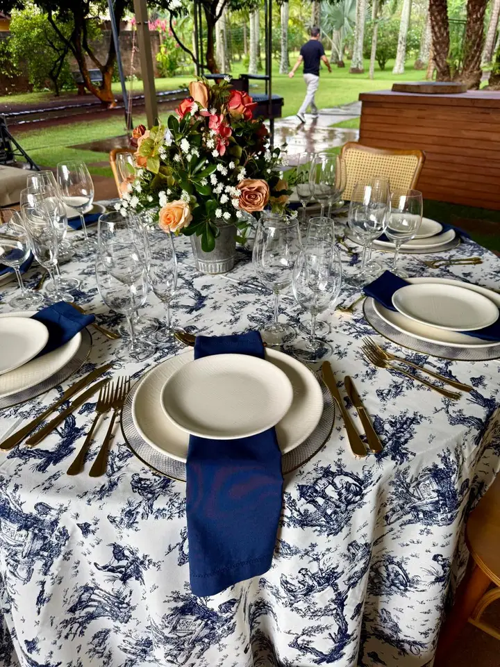 Mesa posta ao ar livre com toalha toile azul, pratos e guardanapos azul-marinho